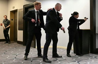 အမေရိကန် သမ္မတ ဒေါ်နယ်ထရန့် တက်ရောက်တဲ့ ညစာစားပွဲမှာ ပစ်ခတ်မှု ဖြစ်ပွား   သတင်းနဲ့ မီဒီယာ ကွန်ရက်။  ၂၀၂၆ ခုနှစ်၊ ဧပြီလ ၂၆ ရက်။   ဝါရှင်တန်ဒီစီရဲ့ ခမ်းနားထည်ဝါလှတဲ့ စနေနေ့ညချမ်းဟာ ရုတ်တရက်ဆိုသလို ထိတ်လန့်တုန်လှုပ်ဖွယ်ရာ အခိုက်အတန့်တွေနဲ့ ပြည့်နှက်သွားခဲ့ပါတယ်။   ဝါရှင်တန်ဟီလ်တန်ဟိုတယ်မှာ ကျင်းပနေတဲ့ အိမ်ဖြူတော်သတင်းထောက်များအသင်း (WHCA) ရဲ့ နှစ်ပတ်လည်ညစာစားပွဲမှာ သေနတ်သံလိုမျိုး ကျယ်လောင်တဲ့ အသံတွေထွက်ပေါ်လာပြီးနောက် သမ္မတ ဒေါ်နယ်ထရန့်ကို လုံခြုံရေးအဖွဲ့ဝင်တွေက အရေးပေါ် ဘေးကင်းရာကို ခေါ်ဆောင်သွားခဲ့ရပါတယ်။   ဖြစ်စဉ်ဖြစ်ပွားခဲ့ပုံ   ဝါရှင်တန်ဟီလ်တန်ဟိုတယ်ရဲ့ ခမ်းမကြီးအတွင်းမှာတော့ တီးဝိုင်းရဲ့ သံစဉ်တွေ၊ ဝတ်စုံပြည့်ဝတ်ဆင်ထားတဲ့ အစိုးရအဖွဲ့ဝင်တွေနဲ့ သတင်းထောက်တွေရဲ့ ရယ်မောသံတွေကြောင့် စည်ကားလို့နေတယ်လို့ အဲဒီပွဲမှာ တက်ရောက်နေတဲ့ သတင်းထောက်တွေက ပြန်ရေးကြပါတယ်။     သမ္မတ ဒေါ်နယ်ထရန့်ဟာ သမ္မတသက်တမ်းအတွင်း ပထမဆုံးအကြိမ်အဖြစ် ဒီညစာစားပွဲကို တက်ရောက်လာတာဖြစ်ပြီး စင်မြင့်ထက်မှာ ဂုဏ်သရေရှိလူကြီးမင်းတွေနဲ့အတူ နေရာယူထားခဲ့ပါတယ်။   ဒါပေမယ့်လည်း ပျော်ရွှင်စရာကောင်းနေတဲ့ အခိုက်အတန့်ဟာ ကျယ်လောင်လှတဲ့ အသံဗလံတွေကြောင့် ရုတ်ချည်းပျက်ပြယ်သွားခဲ့ပါတယ်။   ခန်းမထဲက ဧည့်သည်တွေဟာ "ဝပ်နေကြ! အောက်ဆင်းနေကြ!" ဆိုတဲ့ အော်ဟစ်သံတွေနဲ့အတူ ကြမ်းပြင်ပေါ်ကို မှောက်ချလိုက်ကြရပါတယ်။   "ကျွန်မ စားပွဲအောက်ကိုပဲ ငုပ်လျှိုးနေလိုက်တော့တယ်။ ဘာဖြစ်နေလဲဆိုတာ မသိရတဲ့အတွက် အန္တရာယ်ကို မစွန့်စားနိုင်ဘူးလေ" လို့ One America News သတင်းထောက် Alexandra Ingersoll က အခြေအနေကို ပြန်ပြောင်းပြောပြပါတယ်။   အသံတွေထွက်ပေါ်လာပြီး စက္ကန့်ပိုင်းအတွင်းမှာပဲ လျို့ဝှက် လုံခြုံရေး Secret Service တပ်ဖွဲ့ဝင်တွေဟာ လက်နက်တွေကိုယ်စီနဲ့ သမ္မတကို ဝိုင်းရံလိုက်ကြပြီး စင်နောက်ဘက်ကတစ်ဆင့် ဘေးကင်းရာကို အမြန်ဆုံး ခေါ်ဆောင်သွားခဲ့ပါတယ်။   အဲဒီ အချိန်မှာတော့ ခန်းမထဲက ဂီတသံတွေ ရပ်တန့်သွားပြီး ကြောက်လန့်တုန်လှုပ်နေတဲ့ ဧည့်သည်တွေကြားထဲမှာ လုံခြုံရေးအေးဂျင့်တွေဟာ သေနတ်တွေကိုင်ဆောင်ပြီး နေရာအနှံ့ ဖြန့်ကြက်စစ်ဆေးခဲ့ကြပါတယ်။     ထူးခြားတဲ့ တိုက်ဆိုင်မှုတစ်ခုကတော့ ဒီဟိုတယ်ဟာ လွန်ခဲ့တဲ့ ၄၅ နှစ်က အမေရိကန် သမ္မတ ရော်နယ်ရေဂင် လုပ်ကြံသတ်ဖြတ်ခံရမှုကနေ ကံကောင်းထောက်မစွာ လွတ်မြောက်ခဲ့တဲ့ ဟော်တယ်ပဲ ဖြစ်နေပါတယ်။   ညစာစားပွဲကနေ ဘေးကင်းရာကို အရေးပေါ်ရွှေ့ပြောင်းပေးခဲ့ရသူတွေထဲမှာ ကျန်းမာရေးဝန်ကြီး Robert F. Kennedy Jr လည်း ပါဝင်ခဲ့ပါတယ်။ သူဟာ ၁၉၆၃ ခုနှစ်က လုပ်ကြံခံခဲ့ရတဲ့ သမ္မတ ဂျွန်အက်ဖ်ကနေဒီရဲ့ တူတော်စပ်သူဖြစ်ပါတယ်။   အဲဒီလိုပဲ သမ္မတရဲ့ အုပ်ချုပ်ရေးအဖွဲ့ဝင် တစ်ဦးဖြစ်တဲ့ Mehmet Oz ကလည်း အရေးပေါ်ထွက်ခွာသွားခဲ့ပါတယ်။   ဒီပစ်ခတ်မှု အတွင်းမှာ သမ္မတနှင့် သမ္မတကတော် လုံခြုံဘေးကင်းစွာ လွတ်မြောက်ခဲ့ပြိး အိမ်ဖြူတော်ကို ပြန်လှည့် သွားခဲ့ပါတယ်။   လုပ်ကြံ သတ်ဖြတ်ဖို့ ကြိုးစားခဲ့တယ်လို့ သံသယ ရှိသူ တစ်ဦးကို ဖမ်းဆီးထိန်းသိမ်းထားပါတယ်။   ဝါရှင်တန်ဟီလ်တန်ဟိုတယ် ပတ်ဝန်းကျင်မှာတော့ ရဲတပ်ဖွဲ့ဝင်တွေက လမ်းတွေကို ပိတ်ဆို့ပြီး လုံခြုံရေးအဆင့်မြှင့်တင်ထားသလို၊ ကောင်းကင်ယံမှာလည်း ရဟတ်ယာဉ်တွေနဲ့ ကင်းလှည့်နေပါတယ်။   #အမေရိကန်သမ္မတဒေါ်နယ်ထရမ့် #ပစ်ခတ်မှု #လုပ်ကြံမှု #ဝါရှင်တန်ဟီလ်တန်ဟိုတယ်