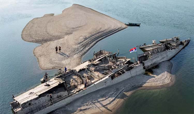 ဥရောပရှိ ဒေးနုဘ် (Danube) မြစ်ရေကျပြီး သမိုင်းဝင် စစ်ကျန် ပစ္စည်းများ ထွက်ပေါ်   သတင်းနှင့် မီဒီယာ ကွန်ရက်။ ၂၀၂၆ ခုနှစ်၊ ဩဂုတ်လ ၂၁ ရက်။   အယ်နီညို ရာသီဥတုကြောင့် ဥရောပတိုက်တွင် အပူလှိုင်းဒဏ်နှင့် မိုးခေါင်ရေရှားမှုများကြောင့် မြစ်ရေများ ကျဆင်းသွားခဲ့ပြီး နှစ်ပေါင်းများစွာ မြစ်အောက်တွင် နစ်မြုပ်နေသောရှေးဟောင်း ပစ္စည်းများ ထွက်ပေါ်လာခဲ့သည်။   ဆားဗီးယားနိုင်ငံ အရှေ့ပိုင်းတွင် ‌ဒေးနုဘ် (Danube) မြစ်ရေသည် စံချိန်တင် ကျဆင်းသွားခဲ့ရာ မြစ်ဝှမ်းအောက်တွင် ရာစုနှစ်တစ်ခုနီးပါး မြှုပ်နှံထားခဲ့သည့် ဒုတိယကမ္ဘာစစ်လက်ကျန် နာဇီစစ်သင်္ဘောပျက်အနည်းဆုံး အစီး ၂၀ ၏ ကိုယ်ထည်များနှင့် ရွက်တိုင်ကျိုးများ ရေမျက်နှာပြင်ပေါ်သို့ ပြန်လည်ပေါ်ထွက်လာခဲ့ပါသည်။   ဤဖြစ်စဉ်၏ သမိုင်းကြောင်းမှာ လွန်ခဲ့သော မနှစ်ပေါင်း ၈၀ ကျော် (၁၉၄၄ ခုနှစ်) က စတင်ခဲ့သည်။   ထိုစဉ်က ဆိုဗီယက် တပ်မတော်၏ ထိုးစစ်ကြောင့် အရှေ့ဘက်စစ်မျက်နှာတွင် နာဇီဂျာမနီတပ်များ ဆုတ်ခွာခဲ့ရပြီး ပင်လယ်နက်အခြေစိုက် နာဇီစစ်သင်္ဘော အစင်း ၂၀၀ ခန့်သည် ဒေးနုဘ်မြစ်အတွင်း ပိတ်မိသွားခဲ့သည်။   ၁၉၄၄ ခုနှစ် စက်တင်ဘာလတွင် ဂျာမနီ စစ်သင်္ဘောအုပ်စုမှ ဒုတိယဗိုလ်ချုပ်ကြီး ပေါလ်-ဝီလီ ဇီးဘ် (Paul-Willy Zieb) က ဆိုဗီယက်တပ်များ၏ သိမ်းပိုက်မှုကို တားဆီးရန်နှင့် မြစ်ကြောင်းပိတ်ဆို့ရန်အတွက် မိမိတို့၏ စစ်သင်္ဘော အစင်း ၂၀၀ ကျော်ကို မြစ်အတွင်း သဘာဝအတိုင်း နစ်မြုပ်စေရန် အမိန့်ပေးခဲ့သည်။   ထိုစစ်သင်္ဘောများထဲတွင် မပေါက်ကွဲသေးသည့် ယမ်းဘီလူးများနှင့် လက်နက်ခဲယမ်းများစွာ ပါဝင်နေဆဲဖြစ်သဖြင့် ရေကြောင်းသွားလာရေးအတွက် ဘေးအန္တရာယ်ကြီးမားစွာ ရှိနေဆဲ ဖြစ်သည်။   ဆာဘီးယားအစိုးရက ထိုသင်္ဘောများကို ဆယ်ယူရှင်းလင်းရန် ယူရို သန်း ၃၀ ခန့် အသုံးစရိတ် လျာထားသော်လည်း အန္တရာယ်များလှသည့်အတွက် လုပ်ငန်းစဉ်မှာ အလွန်နှေးကွေးလျက်ရှိသည်။   ယခုနှစ် နွေရာသီ မိုးခေါင်မှုကြောင့် နာဇီစစ်သင်္ဘောများအပြင် အခြားသော သမိုင်းဝင် ရှေးဟောင်းပစ္စည်းများလည်း ဒေးနုဘ် မြစ်ကြောင်းတစ်လျှောက် ပေါ်ထွက်လာခဲ့သည်-   ဟန်ဂေရီ နိုင်ငံ (ဘူဒါပက်စ်)တွင် ဒုတိယကမ္ဘာစစ်လက်ကျန် ဂျာမနီစစ်တပ်သုံး မော်တော်ဆိုင်ကယ် တစ်စီး၊ ဆလိုဗေးကီးယား နိုင်ငံတွင် ပေါင် ၁,၅၄၃ အလေးချိန်ရှိ မပေါက်ကွဲသေးသည့် ဗြိတိသျှစစ်တပ်၏ လေကြောင်းဗုံးတစ်လုံး၊ ဘူဂေးရီးယားနိုင်ငံတွင် ရှေးဟောင်း ရောမဧကရာဇ် ကွန်စတန်တိုင်း တည်ဆောက်ခဲ့သည့် တံတားဟောင်းအကြွင်းအကျန်များနှင့် နှစ်ပေါင်းထောင်ပေါင်းများစွာ သက်တမ်းရှိ မေးမောက် (Woolly Mammoth) ဆင်စွယ်နှင့် အရိုးများ ဖြစ်သည်။   ဥရောပ၏ ဒုတိယအရှည်ဆုံးဖြစ်သော ကီလိုမီတာ ၂,၈၅၀ မြစ်ကြောင်းတစ်လျှောက် ရေကြောင်းခရီးသွား သင်္ဘောများအတွက် ရေနိမ့်ဆင်းမှုသည် အပျော်စီးခရီးစဉ်များ ဖျက်သိမ်းခြင်းနှင့် ခရီးစဉ်ပြောင်းလဲရခြင်းများ ဖြစ်စေခဲ့သည်။   တစ်ဖက်တွင်လည်း ခရီးသွားများအတွက် သဘာဝအလှတရားနောက်ကွယ်မှ ဥရောပ၏ စစ်ပွဲနှင့် သမိုင်းများကို တိုက်ရိုက်မြင်တွေ့ခွင့် ရရှိစေခဲ့သည်။   #Danube